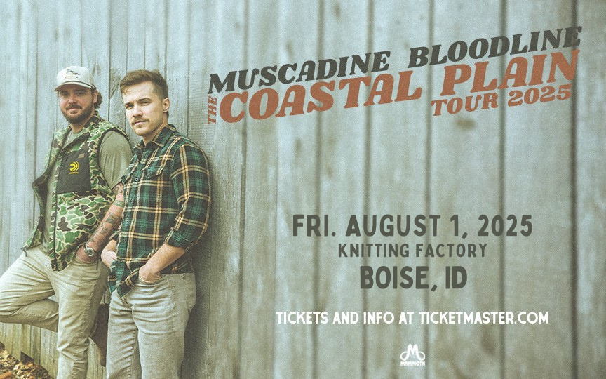 A promotional image for Muscadine Bloodline's Coastal Plain Tour 2025. Two band members stand against a rustic wooden wall, dressed in casual country attire—one wearing a camouflage vest and cap, the other in a plaid shirt and boots. The text announces their concert on Friday, August 1, 2025, at Knitting Factory in Boise, ID, with ticket information available at Ticketmaster.com. The image has a vintage, muted color tone, with bold typography highlighting the tour name.